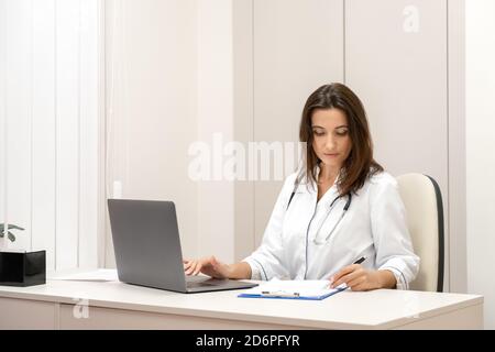 Medico che spiega con il paziente tramite computer portatile, applicazione per la salute mobile. Foto Stock