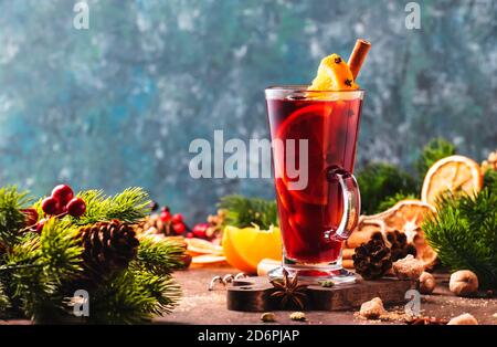 Vino rosso tritato natalizio con spezie e frutta in calice alto su tavola rustica in legno. Tradizionale Natale o NewYear bevanda calda in tavolo di festa Foto Stock