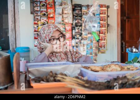 La ragazza nel venditore di stallo hijab è triste quando il negozio è vuoto di acquirenti nel carrello stalla Foto Stock