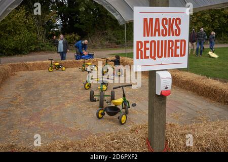 Le maschere hanno richiesto un cartello e un dispenser di disinfettante per le mani in un'area giochi per bambini al festival annuale del raccolto di Fir Point Farm durante una pandemia della stagione autunnale. Foto Stock