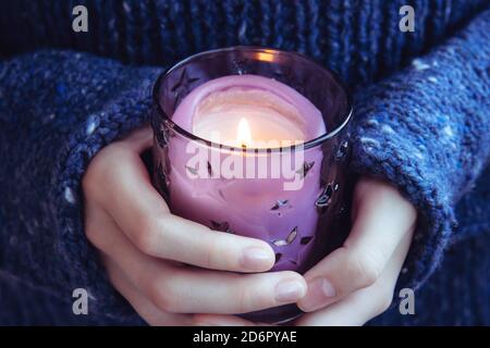 Ragazza in morbido caldo blu scuro maglia maglione tiene in mani che bruciano candela. Candela di Natale. In attesa della vacanza Foto Stock