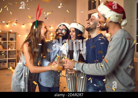 Amici allegri che indossano gli occhiali durante il Natale accogliente o Capodanno festa a casa Foto Stock