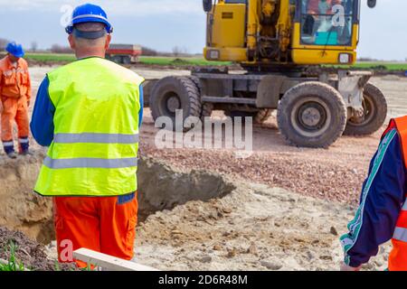 Vista da dietro il lavoratore edile, caposquadra, con blu di sicurezza casco al sito in costruzione, il progetto in corso. Foto Stock