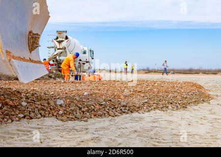 Vista sulla lama della macchina livellatrice, livellatrice, fino a che non è strato livellante di frazione, piccola pietra frantumata in cantiere. Foto Stock