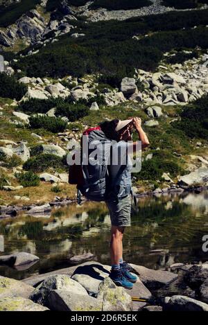 Donna in piedi sulle pietre e guardando la vista di Il lago di rana in montagna Pirin tiro verticale fuoco selettivo Foto Stock