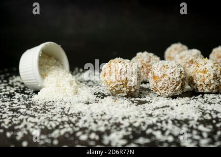 palle energetiche, fiocchi di avena interi e polvere di cocco, dolci a basso contenuto calorico, su sfondo scuro Foto Stock