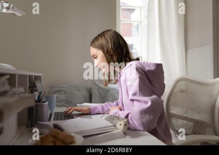 Felice teen studentessa studio sul gioco portatile con il mouse Foto Stock