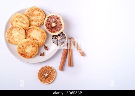 Frittelle di formaggio di cottage. Umore per la colazione di Natale con anice e cannella su sfondo bianco, spazio copia vista dall'alto Foto Stock