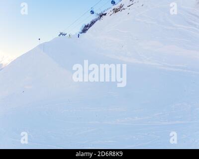 Piste da sci innevate con snowboarder in discesa in lontananza e un sollevatore a pallamano sulla parte superiore Foto Stock