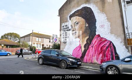 Brighton Regno Unito 19 ottobre 2020 - gli acquirenti passano davanti a un gigantesco murale del cambiamento climatico Greta Thunberg su un muro nella zona del Queens Park di Brighton in un luminoso giorno d'autunno. Il tempo è previsto per diventare più mutevole nei prossimi giorni con vento e pioggia predetto per la maggior parte delle parti del paese: Credit Simon Dack / Alamy Live News Foto Stock