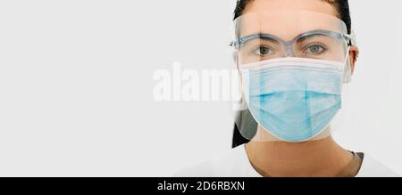 Schermo protettivo e maschera medica dal virus SARS-COV-2 su il volto di un medico praticante durante la pandemia mondiale del coronavirus Foto Stock