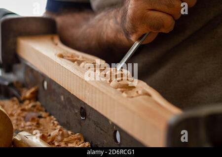 Carpentiere che lavora su mobili in legno con intaglio a mano. Scultura in legno con utensili a mano Foto Stock