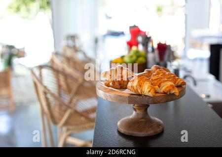 Croissant appena sfornati su un piatto di legno al Cafe Foto Stock