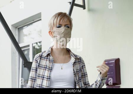 donna bionda lascia la casa in una maschera protettiva Foto Stock