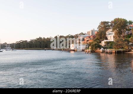 Le case sul bordo dell'acqua a Blues Bay nel porto di Sydney tardi In un pomeriggio di primavera soleggiato preso da McMahons Point Foto Stock