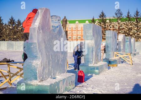 Russia, Birabidzhan, Dicembre 18, 2019: tagli di persone attraverso la scultura di ghiaccio con una sega a nastro Foto Stock