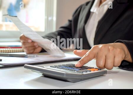 Le donne di affari indossano i vestiti neri con i calcolatori delle dita per calcolare le spese di ufficio. Idee per risparmiare denaro. Foto Stock