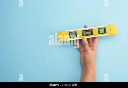 strumento di livello giallo in plastica con presa a mano femmina con capsule su sfondo blu, spazio per la copia Foto Stock