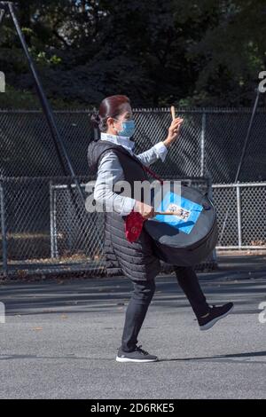 Un membro asiatico americano di un ensemble di batteria prova in un parco in Queens, New York City mentre indossa una maschera chirurgica. Foto Stock