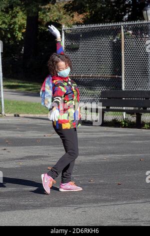 Una donna cinese americana di mezza età in una giacca colorata e sciarpa esercizi di danza con un gruppo in un parco a Flushing, Queens, New York City. Foto Stock