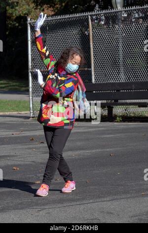 Una donna cinese americana di mezza età in una giacca colorata e sciarpa esercizi di danza con un gruppo in un parco a Flushing, Queens, New York City. Foto Stock