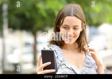 Felice donna che flirta online con smartphone in strada Foto Stock
