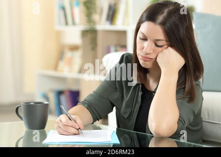 Donna frustrato riempiendo forma seduta nel soggiorno a. casa Foto Stock