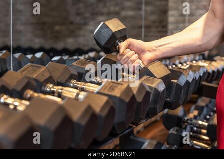 Uomo irriconoscibile che prende un manubri in una palestra da vicino Foto Stock