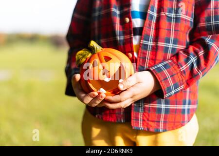 Mano del capretto che tiene la lampada della zucca di Jack'o, trucco o trucco il giorno di Halloween. Concetto per le vacanze autunnali background Foto Stock