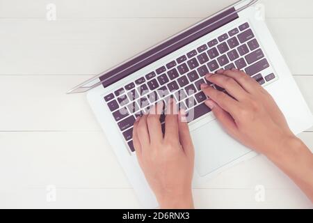Mano di uomo che lavora su computer portatile su tavolo di legno in ufficio, maschio che scrive su notebook sulla scrivania a casa, piatto, spazio di copia, sopra, vista dall'alto, mini Foto Stock