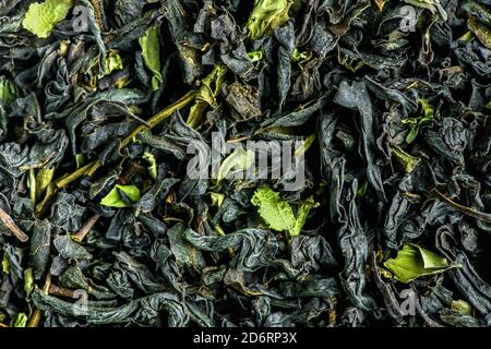 Tè nero a foglia grande come sfondo. Consistenza di foglie di tè nero secche. Foto Stock