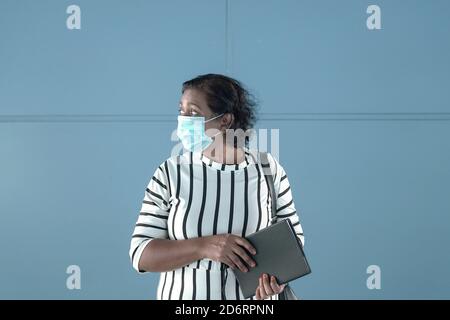 Vista laterale di una donna d'affari che tiene un diario e indossa maschera facciale Foto Stock