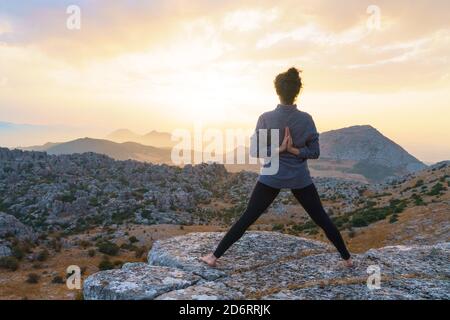 Vista laterale della signora posizionando il piatto con una gustosa torta decorata bloom bud sul tavolo di legno con mazzo di crisantemi, rose e rametti di piante in vaso tra Foto Stock