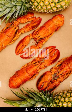 Vista dall'alto di gustose aragoste luminose con conchiglie e artigli vicino ananas fresco intero Foto Stock