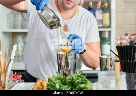 Contenuto femmina etnico che abbraccia American Staffordshire Terrier con lingua fuori mentre si siede in poltrona nella stanza della casa Foto Stock