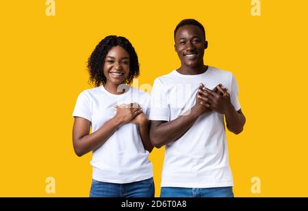 Donna gentile e uomo che tiene entrambi i palmi sul petto Foto Stock