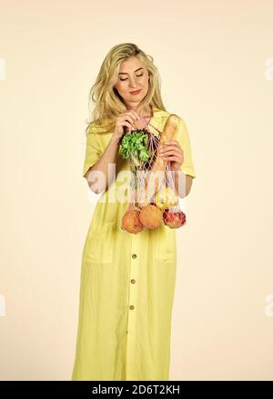 Consumo consapevole. Tendenza ecologica. Concetto di zero sprechi. Ragazza in abito borsa shopper. Donna che tiene la borsa della spesa della stringa con frutta. Sacchetto riutilizzabile. Foto Stock