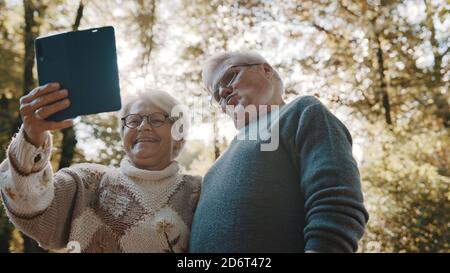 Coppia matura in amore prendendo selfie in foresta il giorno d'autunno. Foto di alta qualità Foto Stock