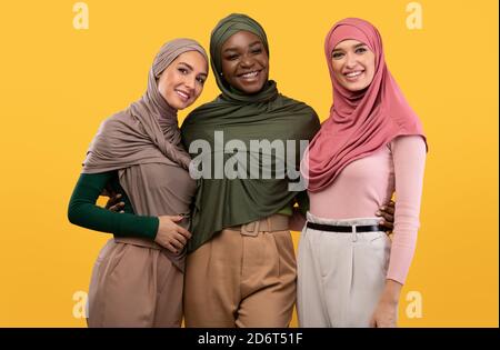 Tre Signore musulmane in Hijab capo in piedi su sfondo giallo Foto Stock