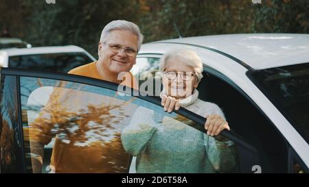 La coppia senior ha acquistato una nuova auto. In piedi vicino alla porta e donna che tiene le chiavi. Foto di alta qualità Foto Stock