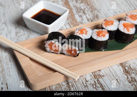 Set di sushi giapponesi di osomaki con filetto di salmone fresco servita su tavola di legno con bastoncini Foto Stock