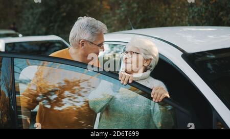 La coppia senior ha acquistato una nuova auto. In piedi vicino alla porta e donna che tiene le chiavi. Foto di alta qualità Foto Stock