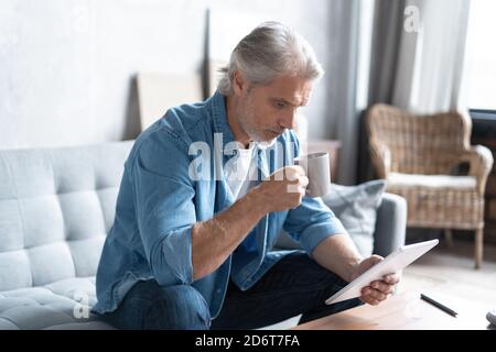 Bell'uomo d'affari che lavora sul tablet da casa. Foto Stock