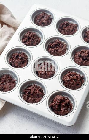 Dall'alto, l'impasto di muffin al cioccolato in un astuccio per muffin durante la cottura padella in cucina leggera Foto Stock