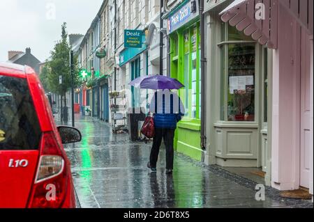 Clonakilty, West Cork, Irlanda. 19 Ott 2020. Una donna cammina lungo una strada principale deserta Clonakilty in mezzo alla pioggia torrenziale questa mattina. Met Éireann ha emesso un avviso giallo di caduta per tutto il paese che scade alle 15 di martedì. Credit: AG News/Alamy Live News Foto Stock