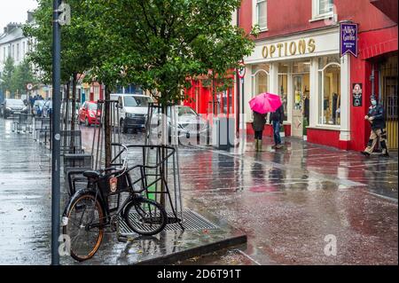 Clonakilty, West Cork, Irlanda. 19 Ott 2020. La gente va circa il loro commercio su una strada principale quasi deserta di Clonakilty fra la pioggia torrenziale questa mattina. Met Éireann ha emesso un avviso giallo di caduta per tutto il paese che scade alle 15 di martedì. Credit: AG News/Alamy Live News Foto Stock