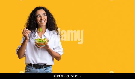 Donna allegra mangiare insalata di verdure da ciotola e guardando Copia spazio Foto Stock