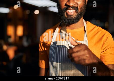 Barbiere maschio sorridente che regge il rifinitore portatile per capelli Foto Stock