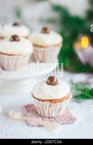 Angolo di gustosi cupcake decorati con palle di cioccolato e. Cosparso di fiocchi di cocco messi a tavola per le celebrazioni natalizie Foto Stock