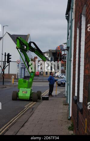 Lavoratori che utilizzano un sollevatore del braccio Rider 12 in altezza per raggiungere un finestrino sulla High Street di BOSTON nel Lincolnshire, Foto Stock